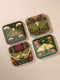 A set of four square hardboard coasters with smoothly rounded corners and a protective high-gloss finish. Each coaster features a unique, highly detailed Art Nouveau style illustration of a moth centered against a dark, botanical background. The intricate artwork uses a rich, moody color palette of deep forest greens, ochre, muted olive, crimson, and black, evoking a vintage, scholarly feel. These decorative drinkware accessories are designed for coffee table and bar cart use.